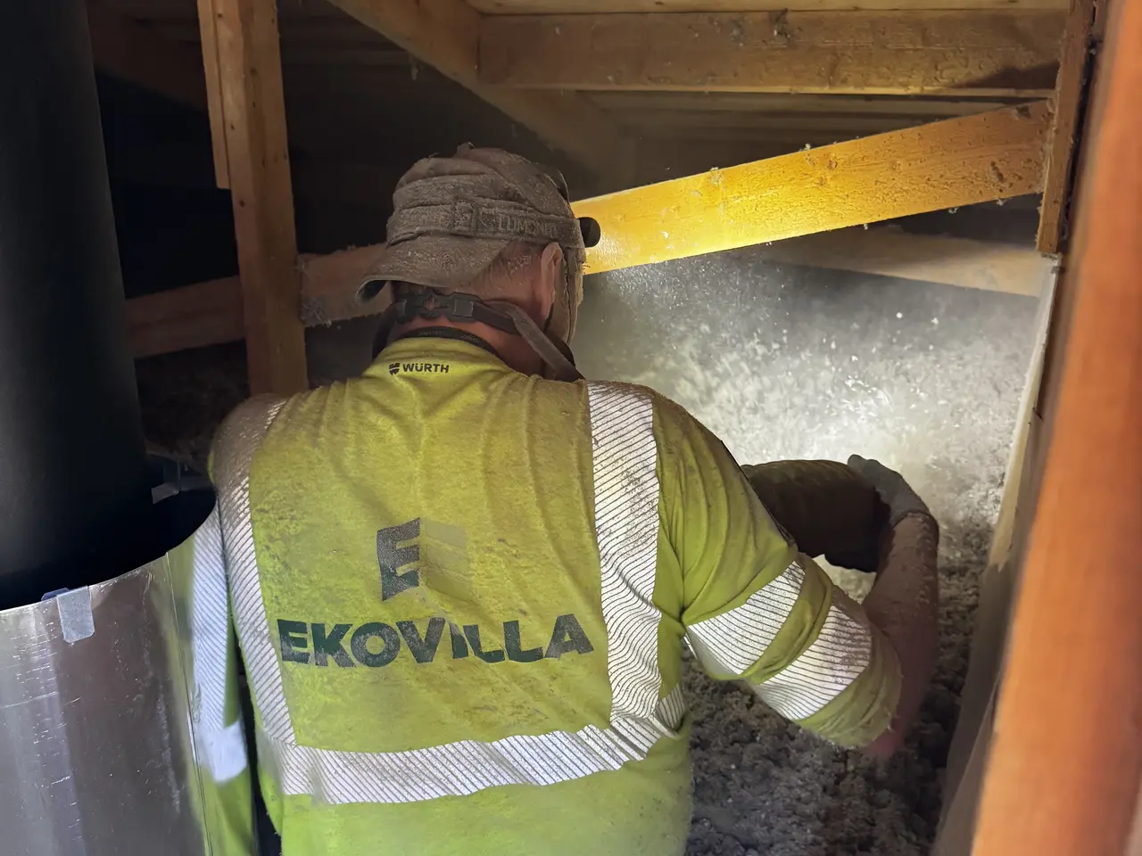 Ekovilla-installatör vid en vindslucka med isoleringsslang